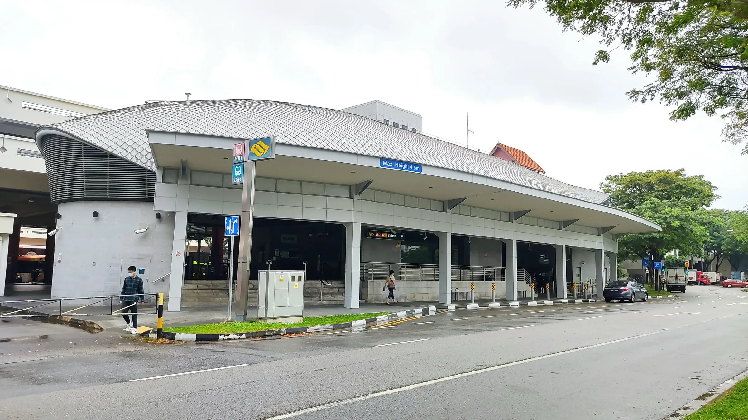 Exit D of Bishan MRT station, a low building with a curved silver roof beside the road